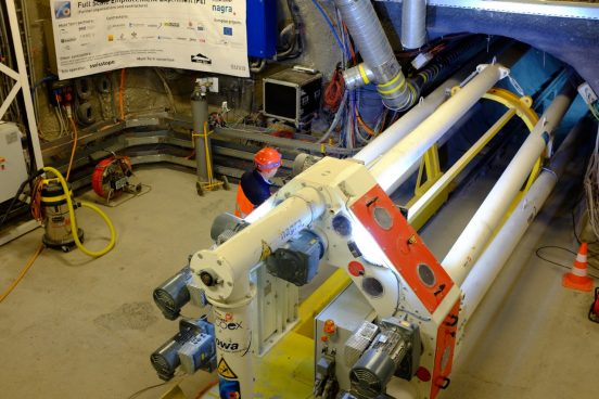 Installation des Prototyps der nach Mass angefertigten Bentonitverfüllungsmaschine um die Verfüllungstechnik im Pilotstollen zu testen. Das Foto zeigt die Verfüllungsmaschine und einen Arbeiter.