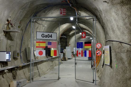 La photo illustre l'entrée du laboratoire souterrain, à la porte sont les drapeaux de tous les partenaires.